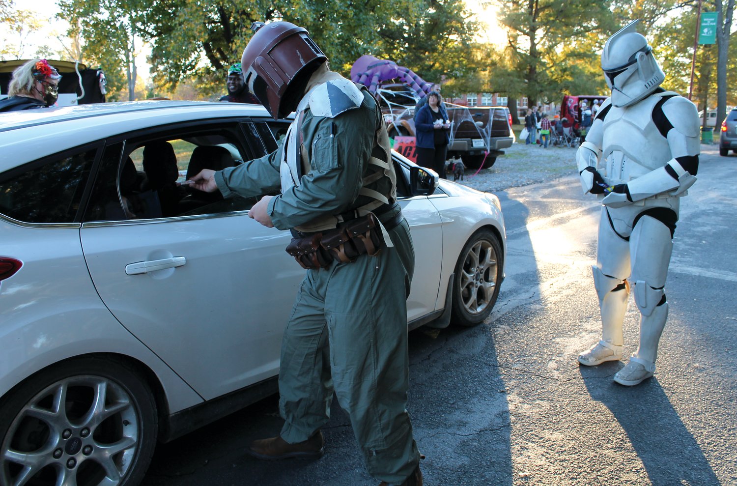A Mandalorian, aka Brent Woodside, and a Storm Trooper give treats to children in a vehicle passing by their booth at the 2020 drive-thru trunk-or-treat event hosted by Sedalia Parks and Recreation at Liberty Park. Brent and his wife, Kayla, are artists for Disney and LucasFilms, so their Star Wars costumes were appropriate for the event. As they ran out of candy, they began drawing quick sketches of Baby Yoda to hand out to kids.