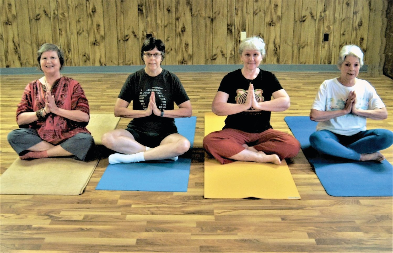 Irene Renauld, Irma Schmidt Davis, Audrey Martens Conner, Tanja Tagtmeyer, with hands in Anjali Mudra (also known as Prayer Mudra), and legs in Sukhasana (aka Easy Pose).